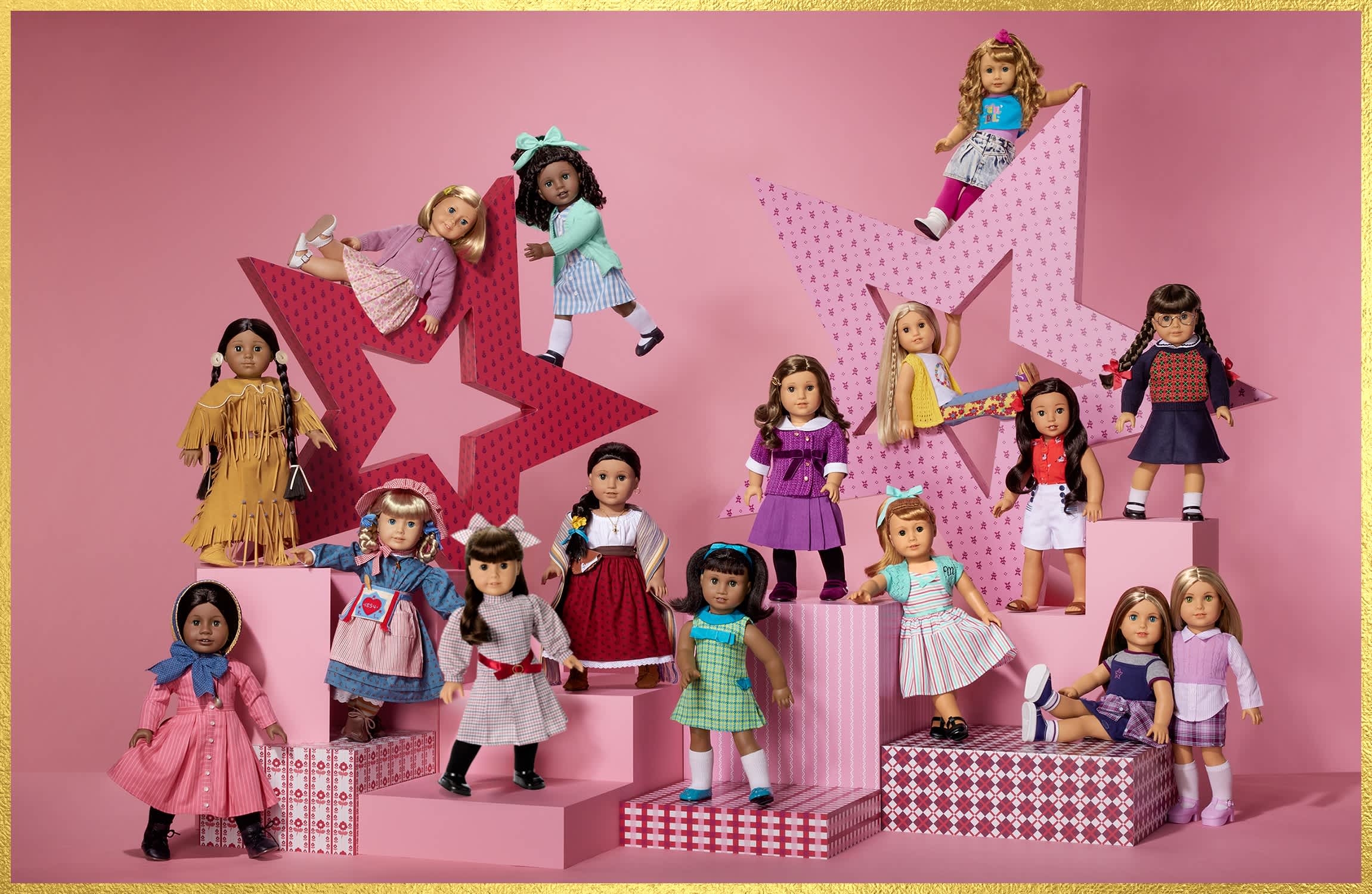 A display of American Girl historical character dolls arranged on pink platforms with star-shaped backdrops. Dolls from various eras stand and pose together wearing their signature outfits.